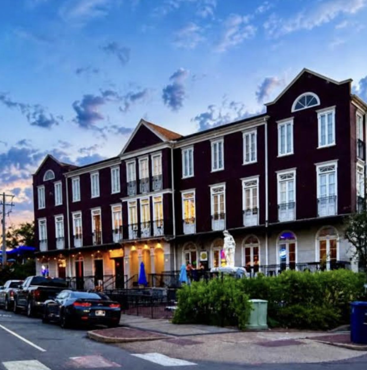 Three-story maroon Cotton District townhouses with white trim and balconies at dusk
